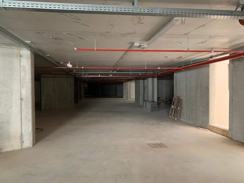 Interno di un edificio in costruzione con strutture in cemento e impianti a vista.