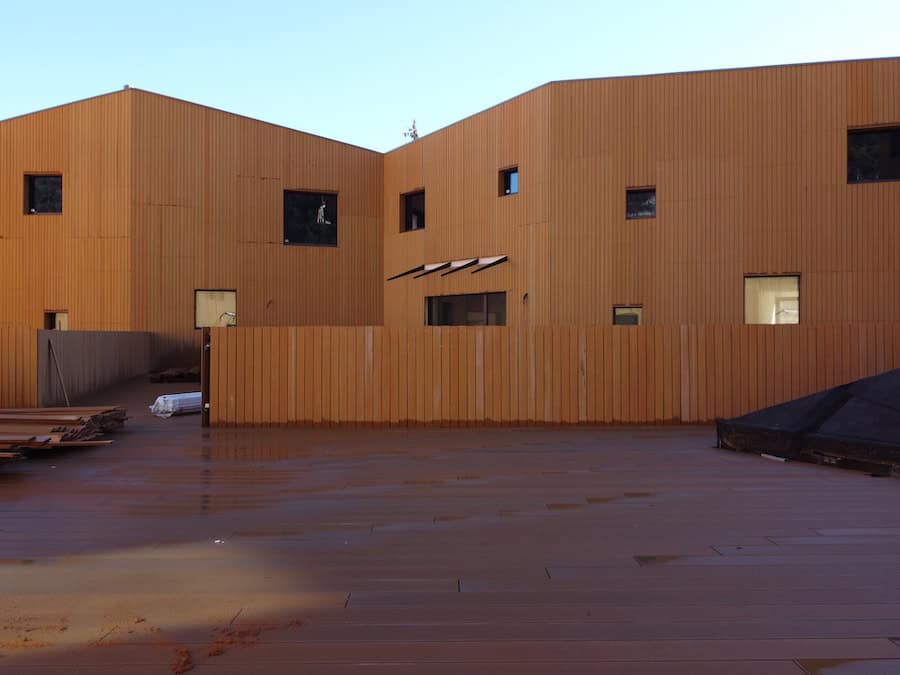 Edificio in legno con finestre e area esterna in fase di completamento.