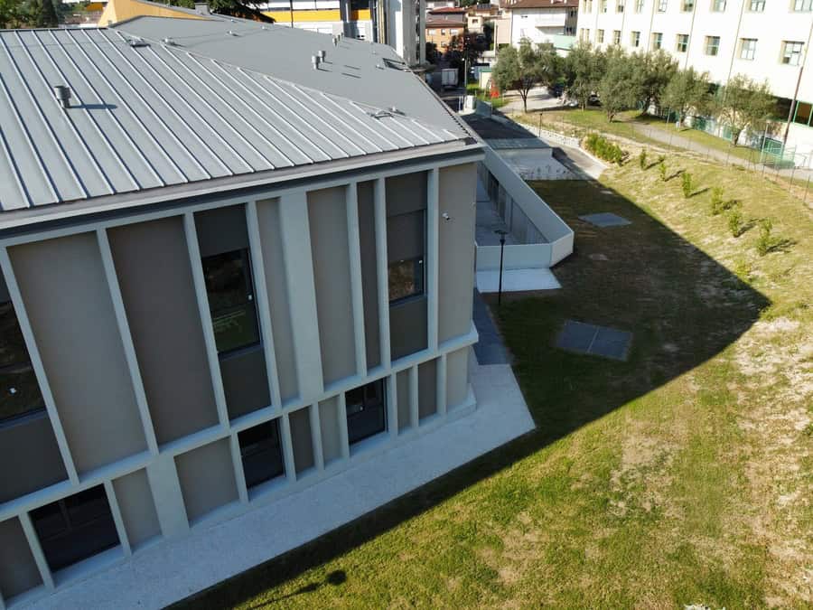 Edificio moderno con grandi finestre e area verde circostante a Riva del Garda.