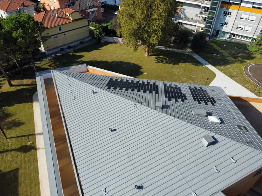 Tetto di edificio con pannelli solari e copertura in metallo a Riva del Garda.