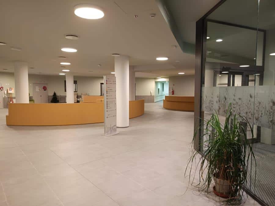 Interno della Cittadella dell’accoglienza Riva del Garda con reception e piante.