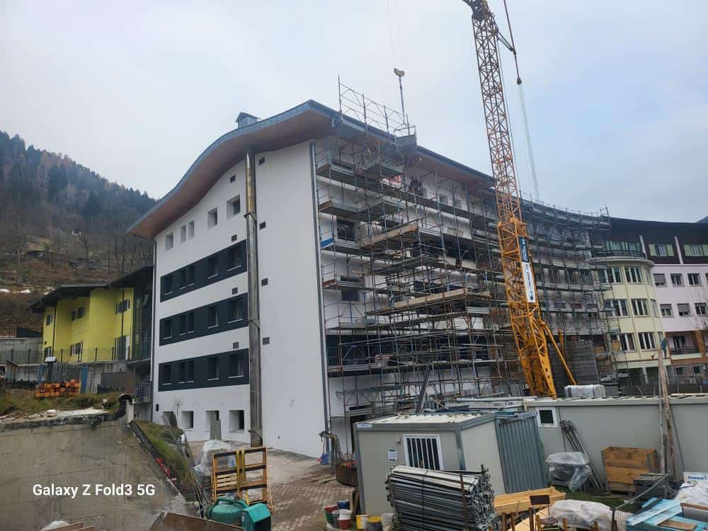 Costruzioni Dallapè Srl lavora alla ristrutturazione di un edificio con impalcature e gru.