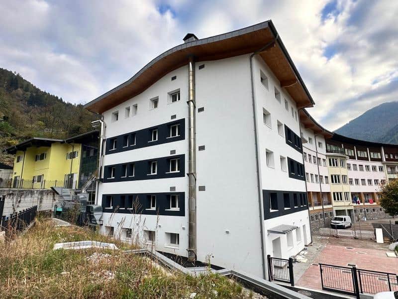 Edificio residenziale in fase di ristrutturazione con vista sulle montagne.